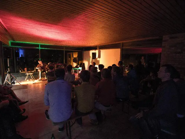 In this picture we can see some people sitting in the hall and listening to the music. Behind we...