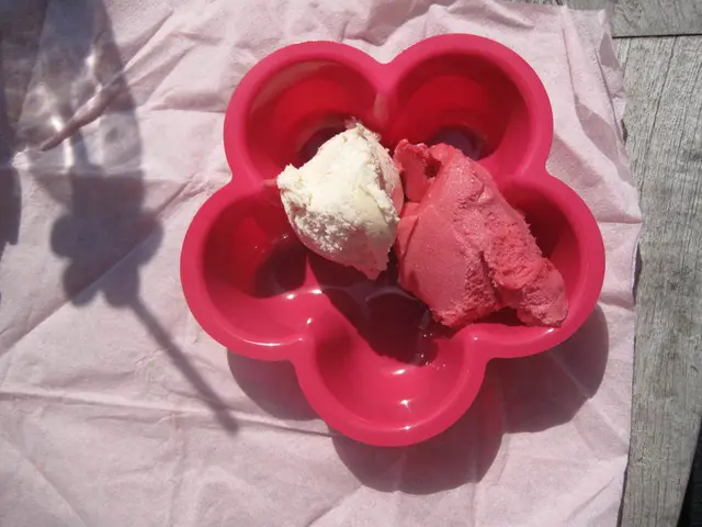 In this image I can see a white and red color ice-cream in red color plate. Plate is on the pink...