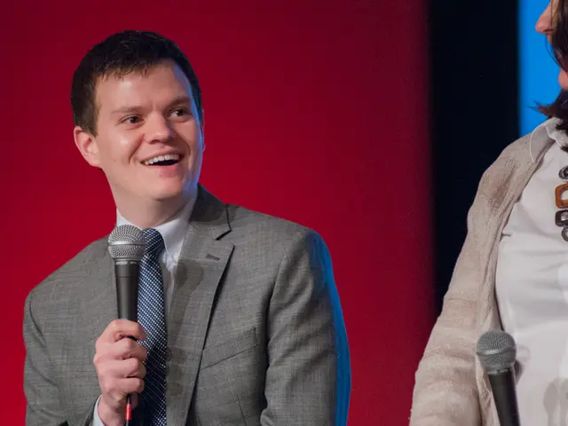 This picture shows a man holding a microphone in his hand with a smile on his face and a woman...