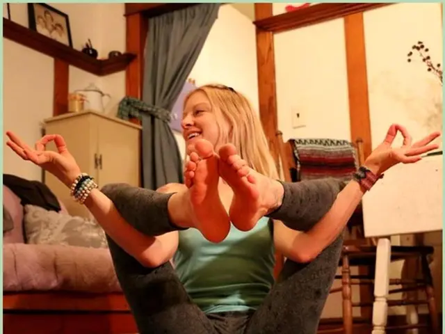 In this image we can see a room. In the room there are a woman sitting on the mat and performing...