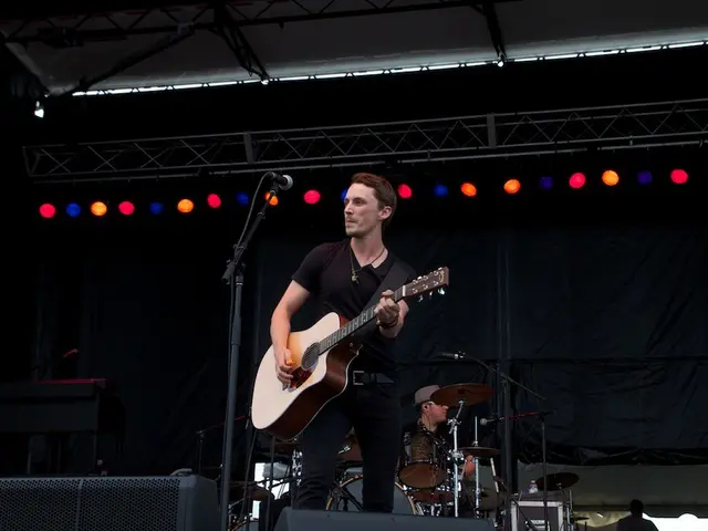 This is a picture of a concert. In this image there is a stage. In the center of the image there is...