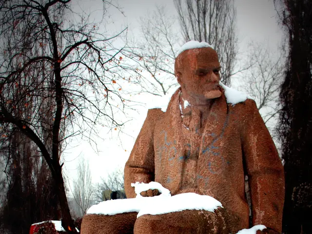 There is a sculpture of a person at the center, he is sitting. There is snow around it. There are...