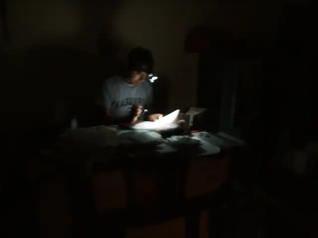 in this picture we see a man seated and reading a paper with the help of a lamp